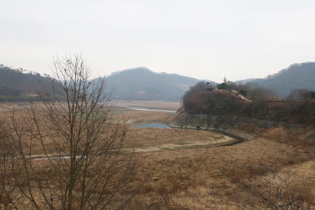 저수지 물이 차 있었던 곳이 풀밭으로 변하고 작은 개울만 흐르고 있다.