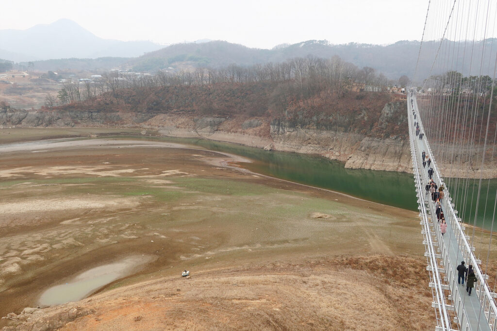 오른쪽에 출렁다리가 화면 위아래로 놓여 있고, 왼쪽엔 옥정호의 바닥이 드러나 있다.