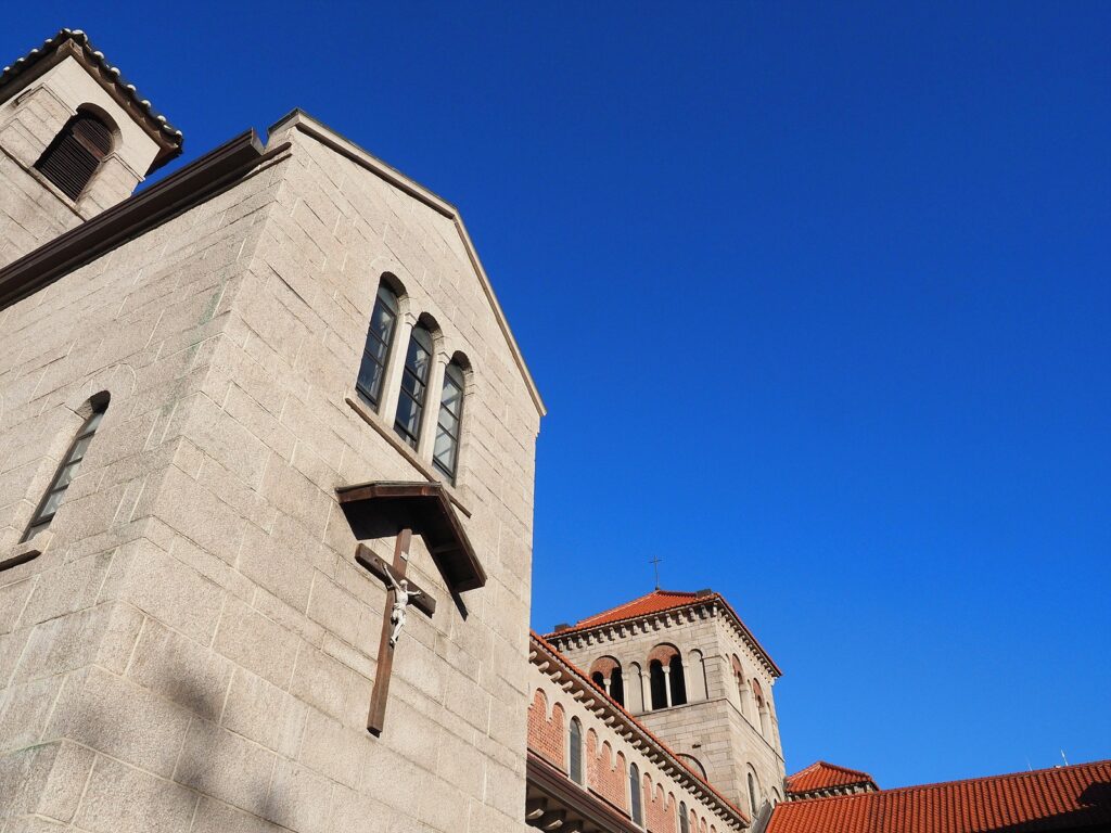 빛을 받아 밝게 빛나는 성공회 서울주교좌성당의 십자가 걸린 한쪽 벽. 배경으로는 파란 하늘이 깔려 있다.