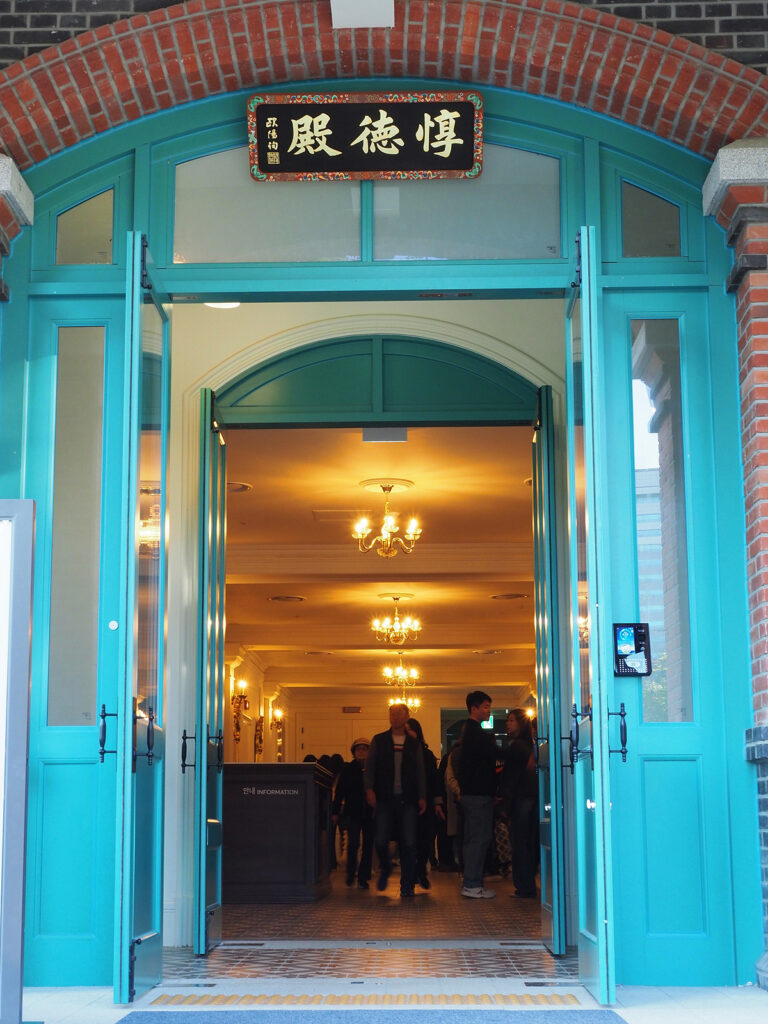 덕수궁 돈덕전 입구와 현판을 촬영한 사진으로, 문틀은 옥색으로 칠해져 있고 내부에는 근대 유럽풍 샹들리에 조명이 달려 있다.