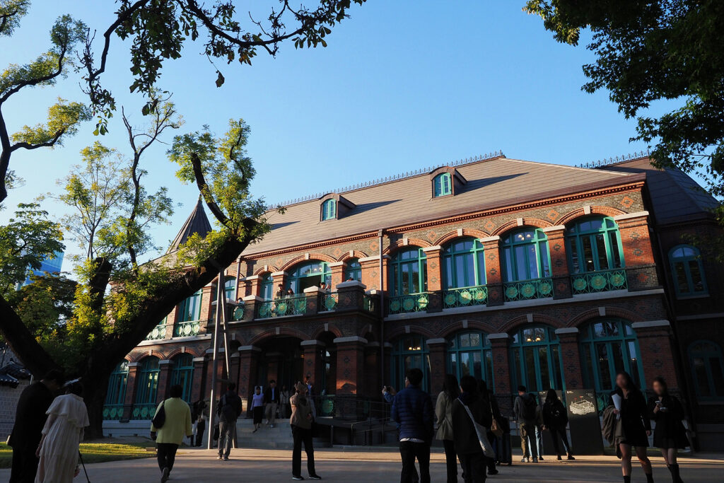 붉은 벽돌로 된 서양식 건물 돈덕전. 왼쪽엔 회화나무가 서 있다.