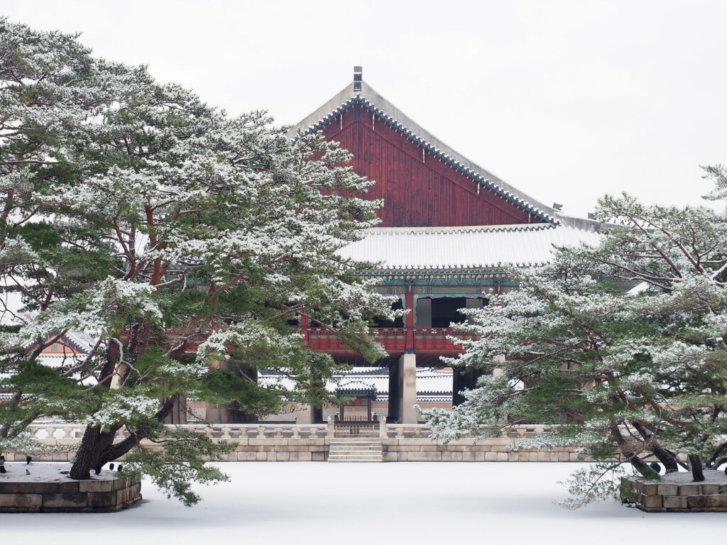 경복궁 경회루를 측면에서 바라본 모습. 소나무 두 그루가 좌우에 걸쳐 있다. 그 앞으로 펼쳐진 공간은 얼어붙은 연못으로, 언뜻 봐선 땅과 구분하기 어렵다.