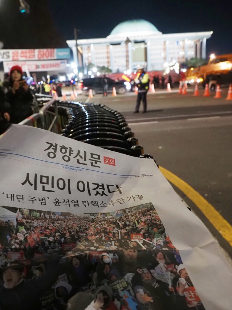 "시민이 이겼다"라는 제목이 찍혀 있는 경향신문 호외판. 그 뒤로 국회의사당이 보인다.