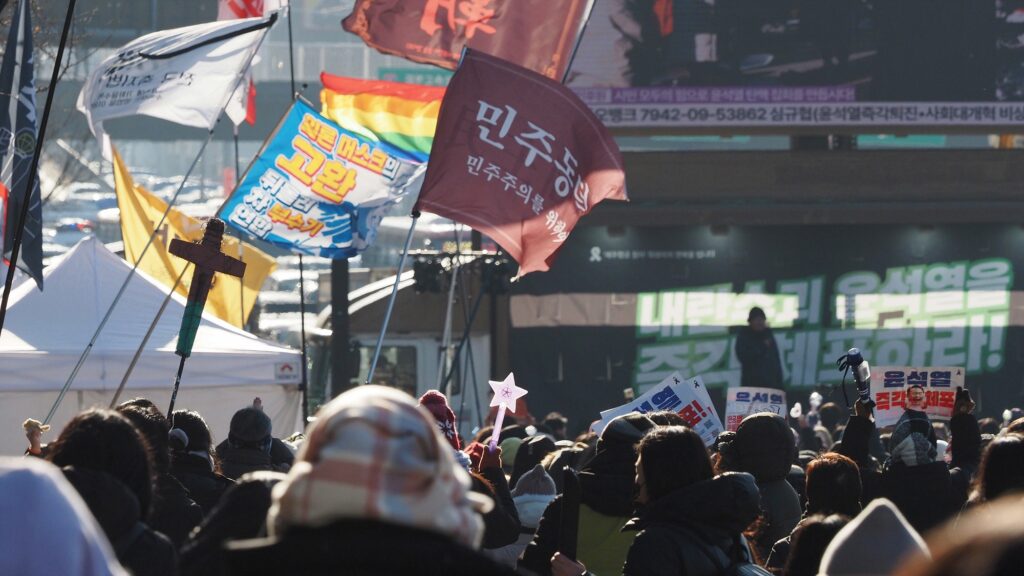 수많은 시민이 모여있는 가운데, "민주동덕" "일론 머스크의 고환 뒤돌려차 부수기 연합", 성소수자를 의미하는 무지개 깃발 등 다양한 깃발이 보인다.