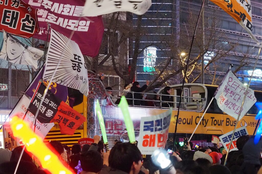 노란 2층 시티투어 버스에 탄 승객들이 집회 중인 시민들을 향해 인사하고 있다.