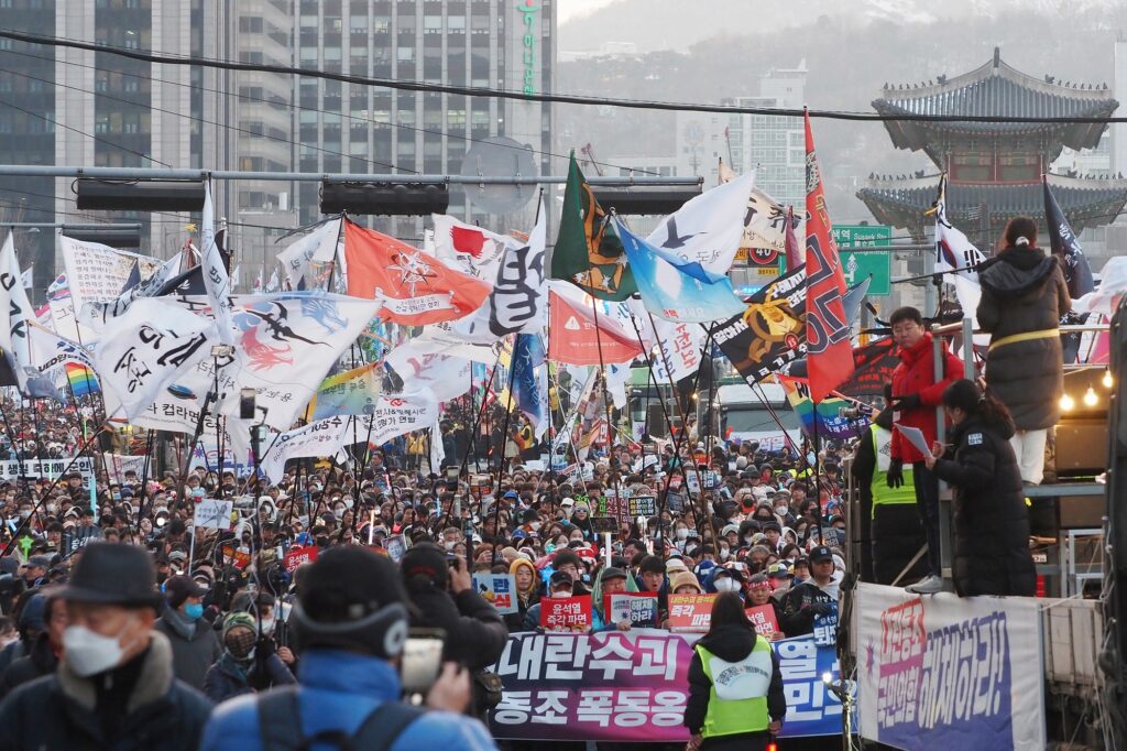 수많은 깃발과 손팻말이 보이는 가운데 모여 행진하는 시민들.
