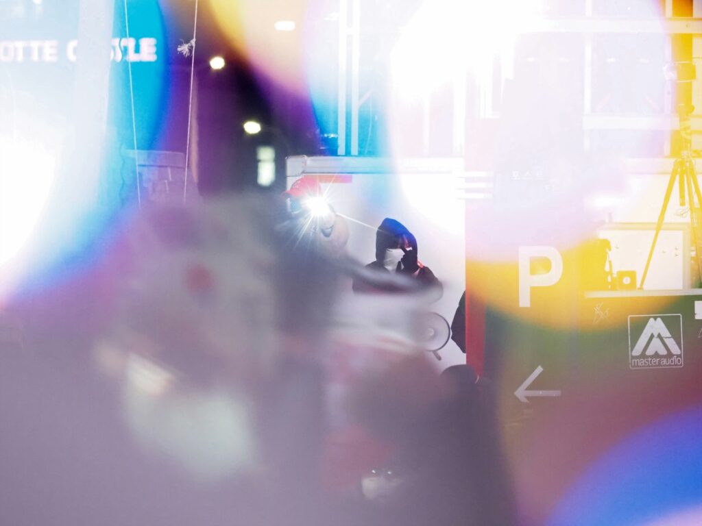 흐릿한 빛망울들 사이에서 반대편 지지자가 가운뎃손가락을 들어 보이는 모습.