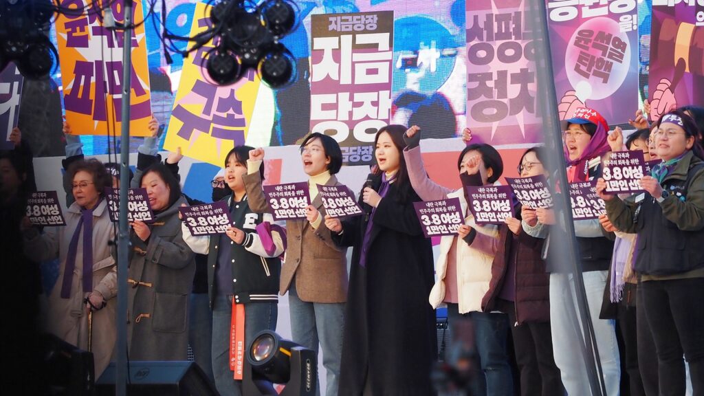 보라색 손팻말을 든 여성 대표들이 무대에서 선언문을 낭독하는 모습.