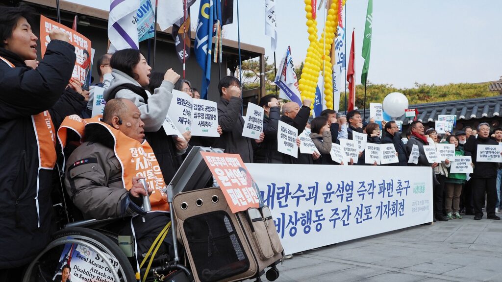 "내란수괴 윤석열 즉각 파면 촉구 비상행동 주간 선포 기자회견"이라 적힌 현수막과 기자회견 중인 시민들.