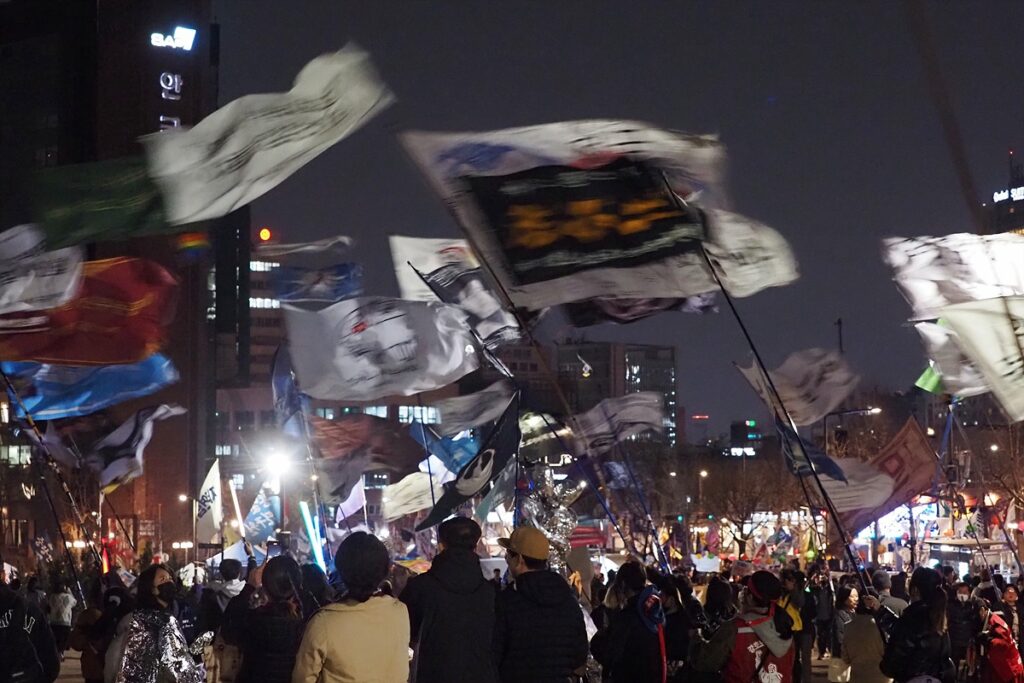 안국역 앞에서 이뤄진 야간 집회 모습. 응원봉 불빛이 반짝이는 가운데 수많은 깃발이 함께 나부끼고 있다.
