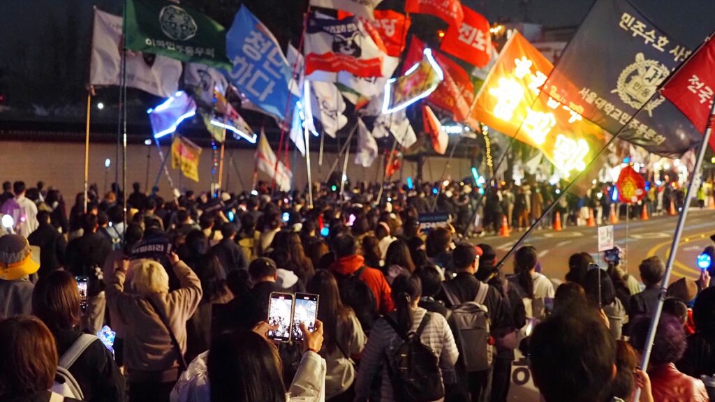 시민들이 깃발, 응원봉 등을 든 채 광화문 앞 길을 행진하고 있다.